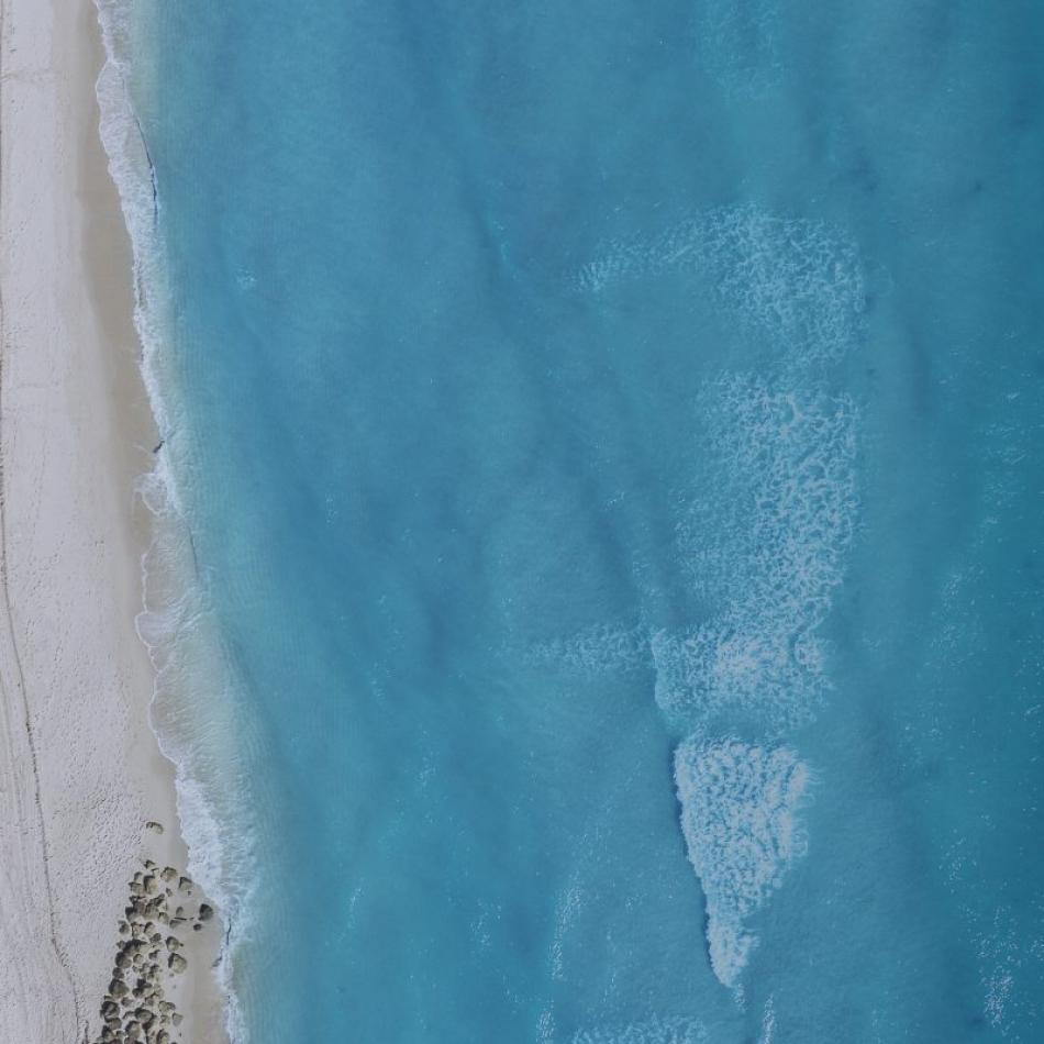 aerial view of blue ocean and white sand beach with red and white umbrellas