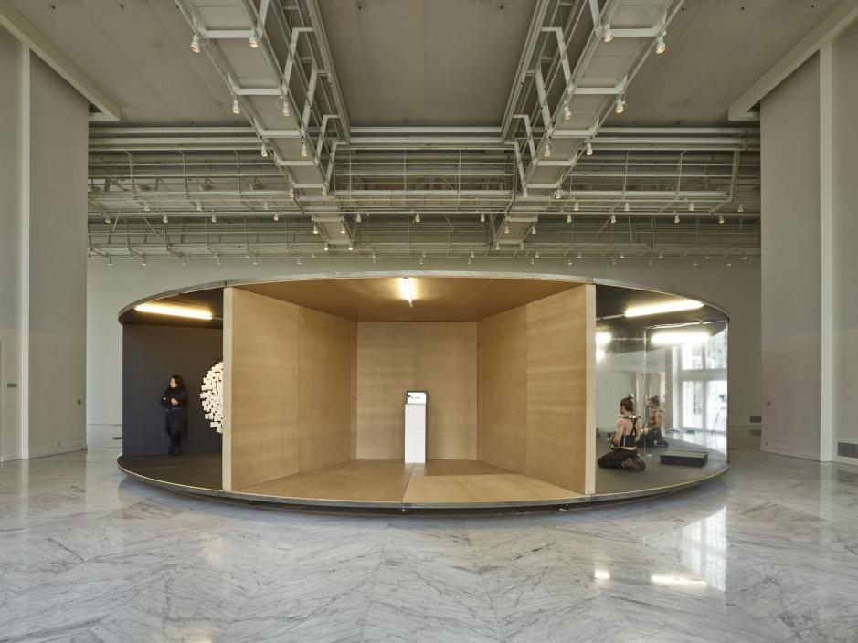 A wooden carousel split into sections with individuals performing in each section