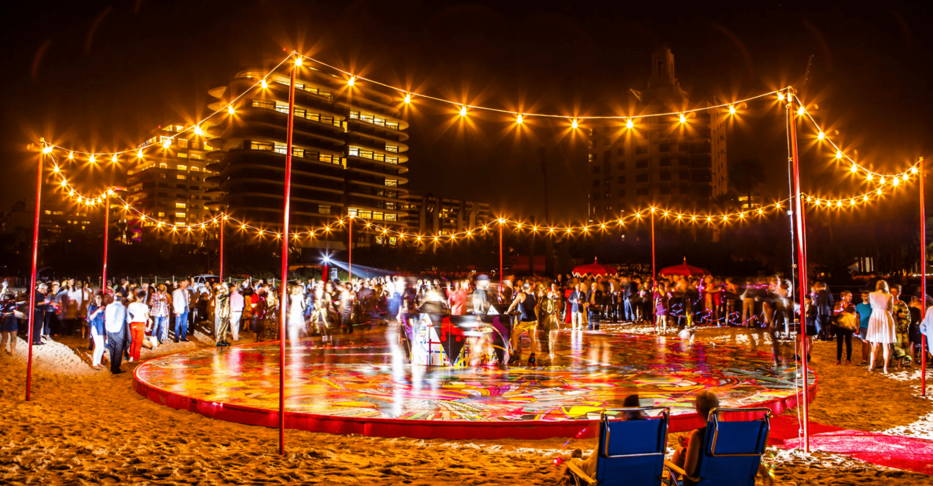 An elevated platform covered in murals on the beach with lights and people rollerskating