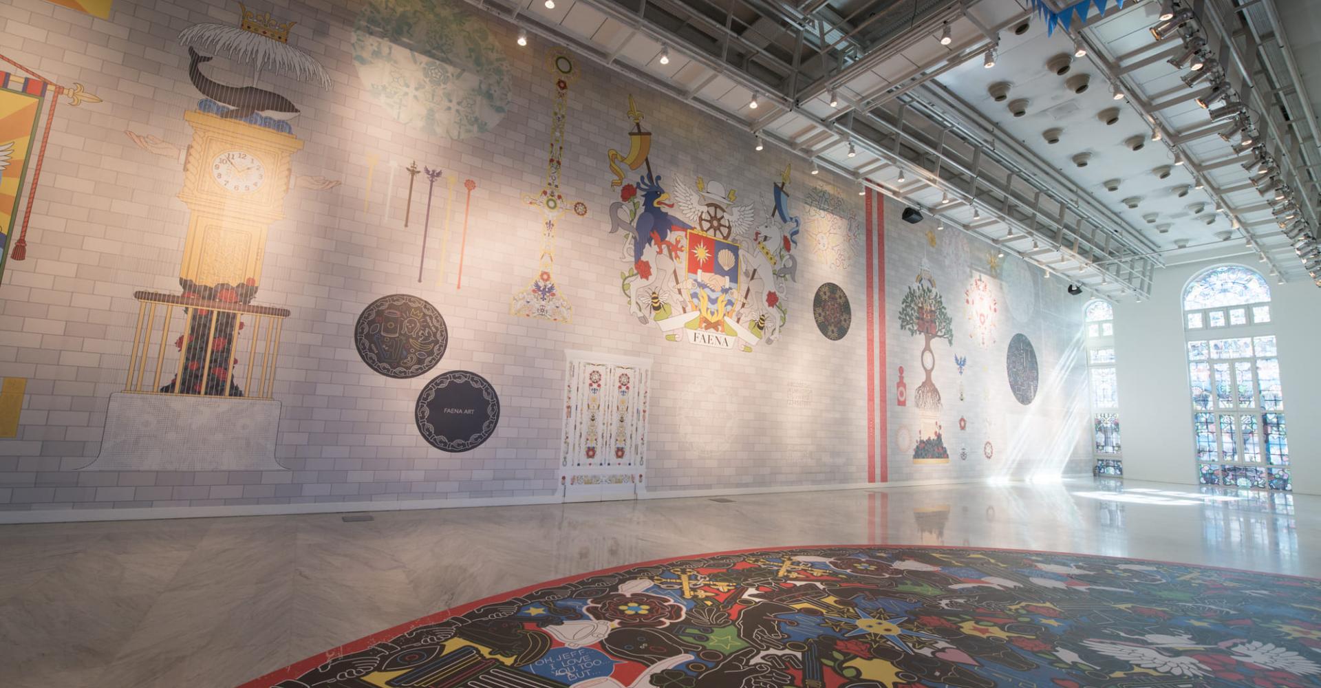 A room with murals along the wall and the floor with large stained glass windows