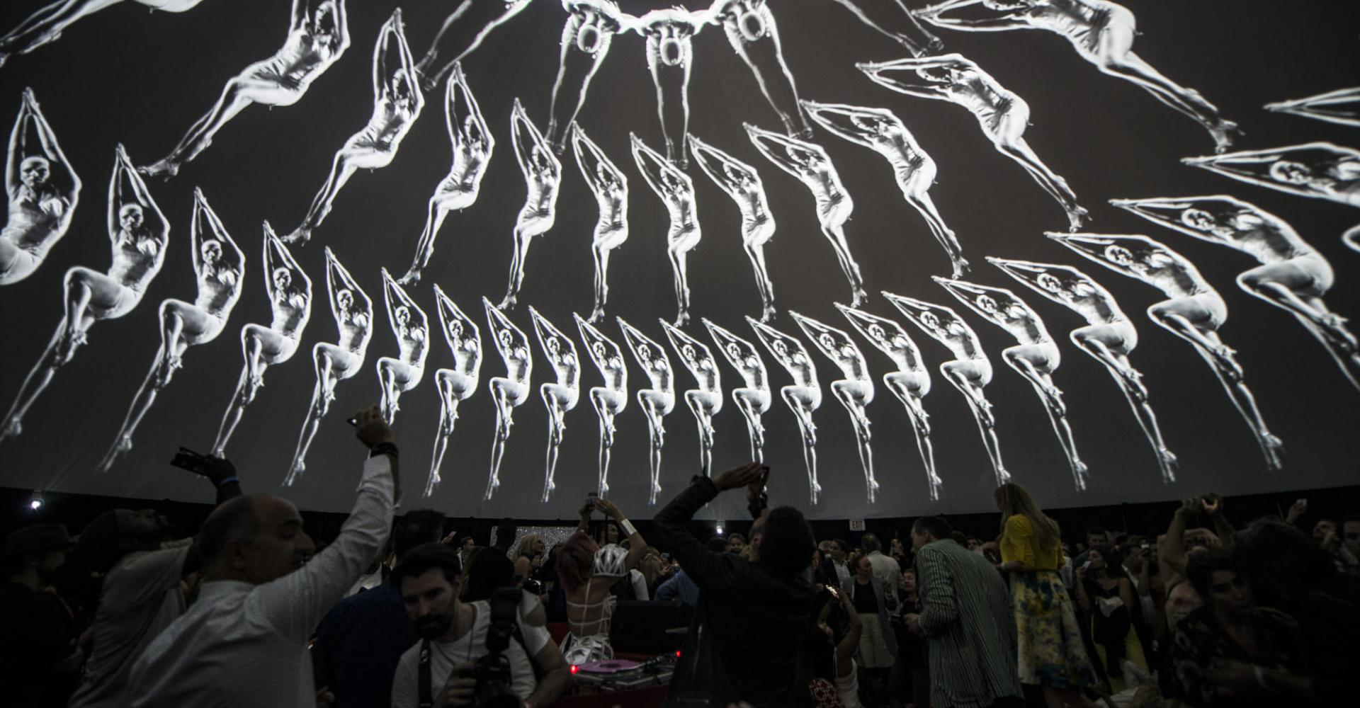 People viewing an art installation on a dome ceiling